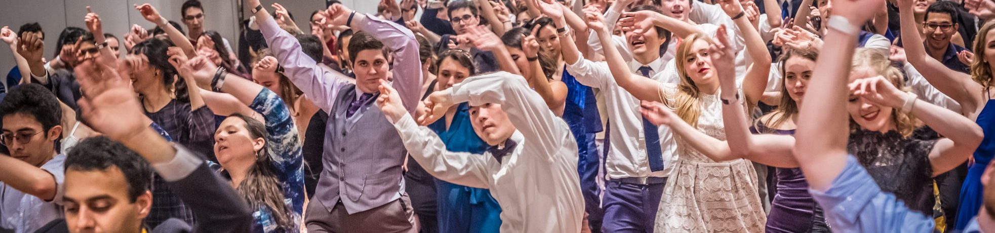a large crowd of dancers raise their hands in the air